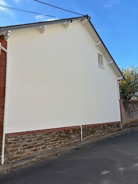 Façade claire rénovée, avec soubassement en pierre et briques
